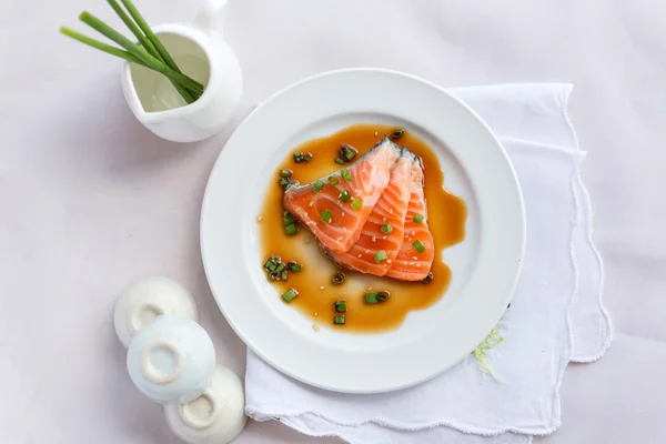 Salmon fillet with sauce on white dish