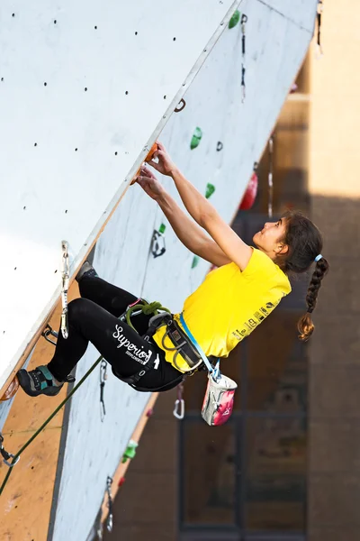 Junior female Athlete makes hard move on climbing Wall