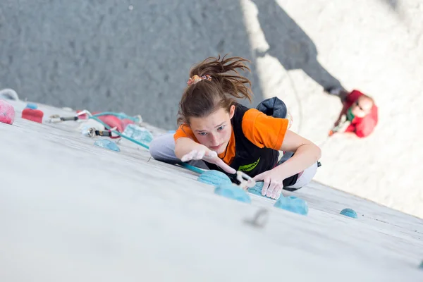 Junior female Athlete makes hard move on climbing Wall