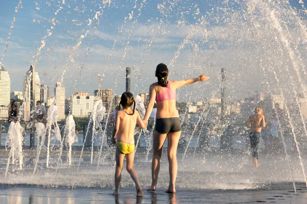 People fleeing from the heat in a city fountain in the centre of a European city