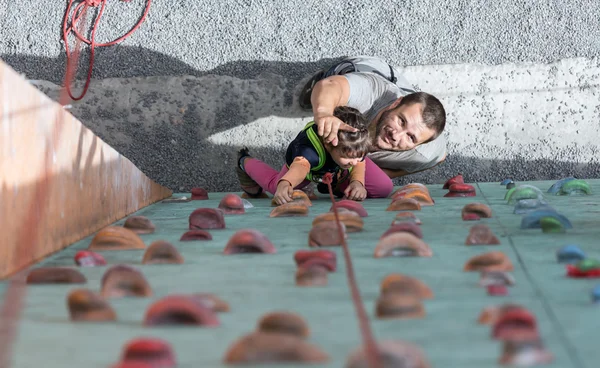 Father teaching his little baby daughter rock climbing
