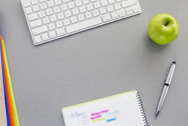 Office work space on grey desk with green apple