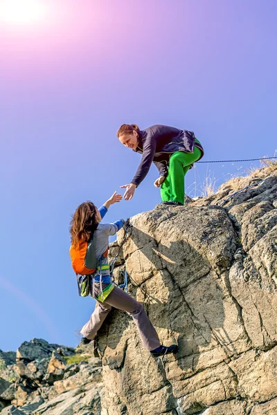 Female climbers helping each other on rock wall