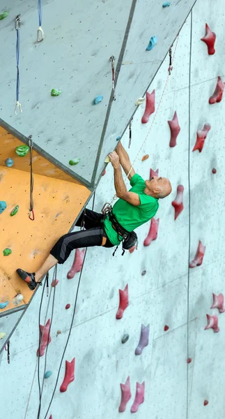 Aged Man Ascends Climbing Wall