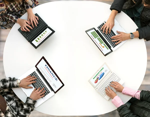 Top View of Rounded Desk with Four Laptops and People Hands Typing on Keyboard