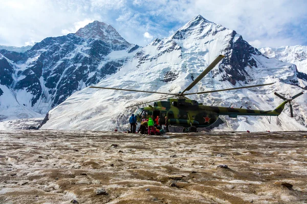 Helicopter Landing on Ice Field of Massive Glacier and People Unloading Luggage