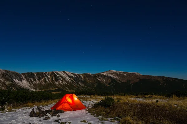 Night mountain landscape with illuminated tent