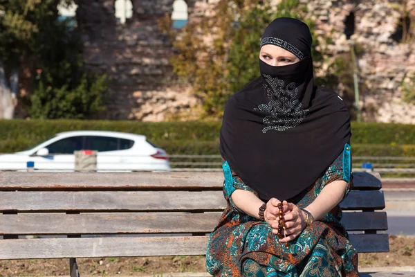 Muslim Style dressed Lady sitting on wooden Bench Sad