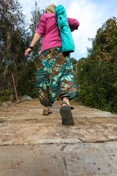 Woman walking on old wooden bridge with yoga bag Foot Close Up