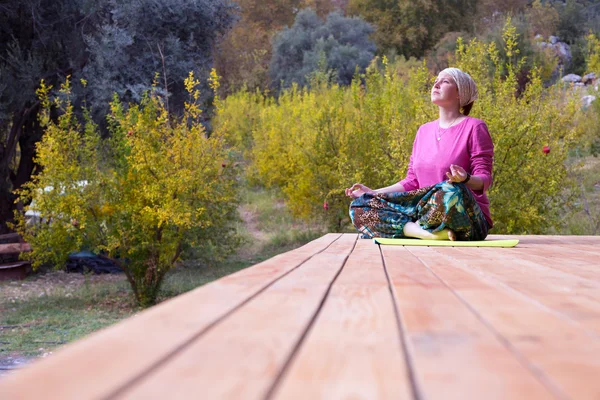 Person doing Yoga Exercise on wooden Terrace of rural Cabin