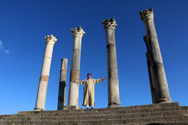 Greek man in national dress in the antique columns