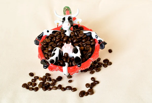 Ceramic figure: cow sitting in the red cup with coffee beans like in bath