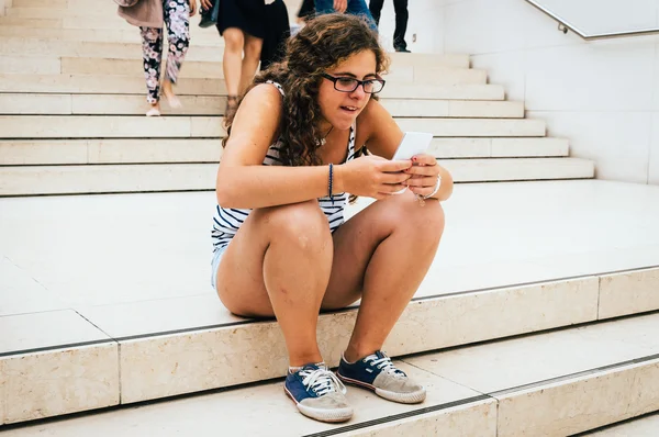 Young woman in a stair with a smartphone