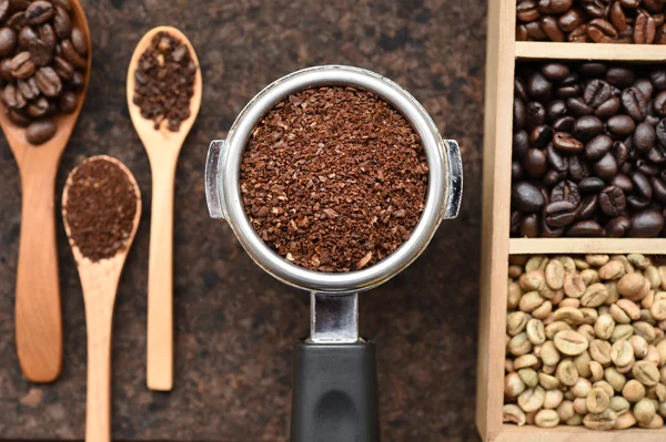Coffee beans with freshly ground coffee beans in a metal filter and ground coffee in wooden spoon
