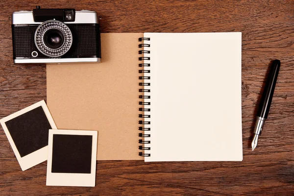 Blank notebook with pen, photo frames and camera