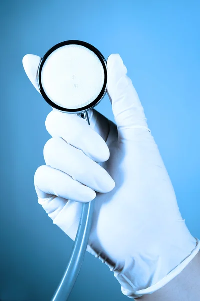 Hand holding a stethoscope take with blue filter