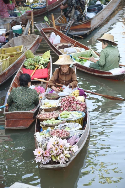 Wooden boats are loaded with fruits from the orchards at Tha kha floating market .