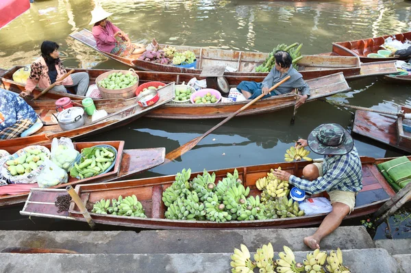 Wooden boats are loaded with fruits from the orchards at Tha kha floating market