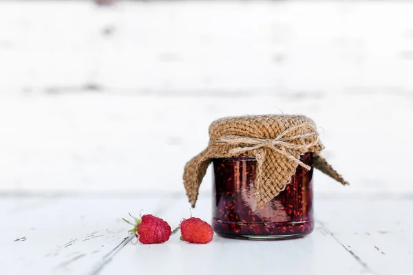 Raspberry jam in a jar on the wooden table