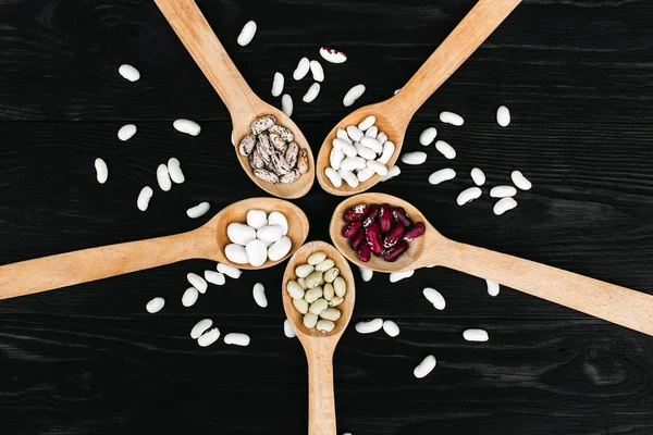 A colorful of beans in wood spoon on wood background