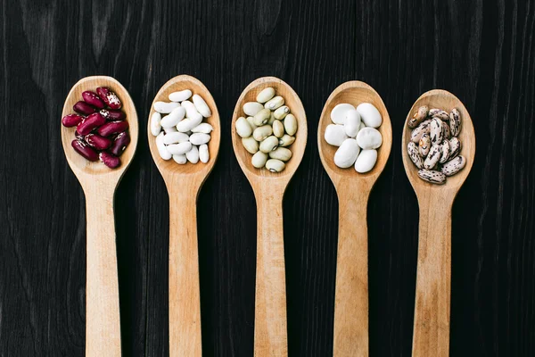 A colorful of beans in wood spoon on wood background