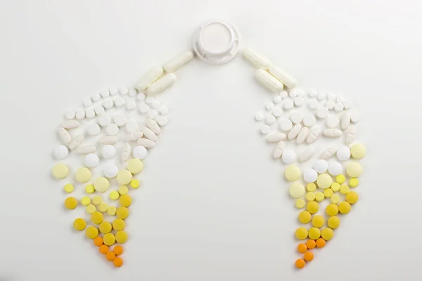 Tablets on a white background in white, yellow, orange syringe w