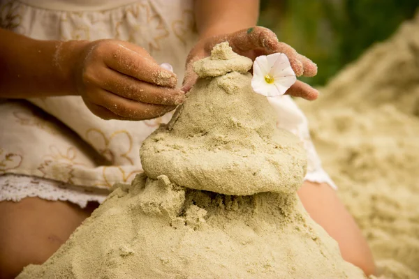 The hand of a little girl out of the sand mold cake