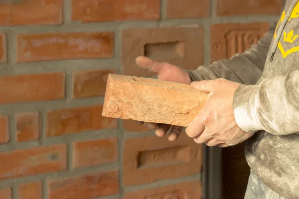 Men's hands are kept carved brick on brick wall background, man'