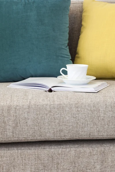 Coffee and book on Sofa with pillow