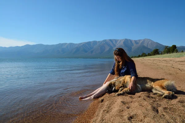 Girl with a dog on the shore of Lake Baikal