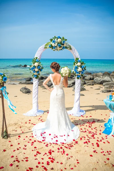 Girl in wedding dress in the background of wedding arches on the seafront