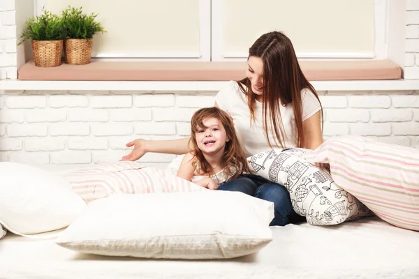 Mother and daughter lying in bed with pillows