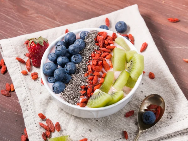 Smoothie bowl with strawberry smoothie, berries, kiwi and chia