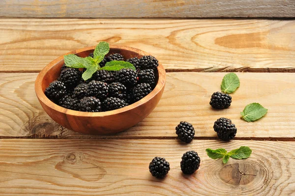 Blackberries in a wooden bowl with mint leaves