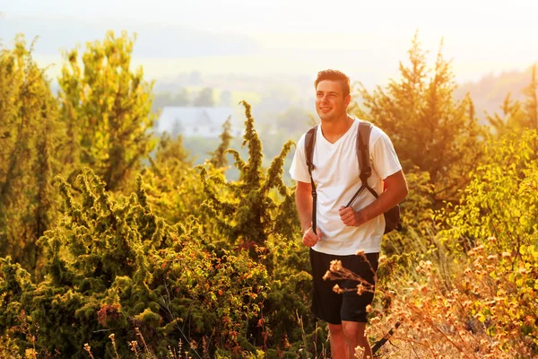 Close up of smiling young man hiking with backpack