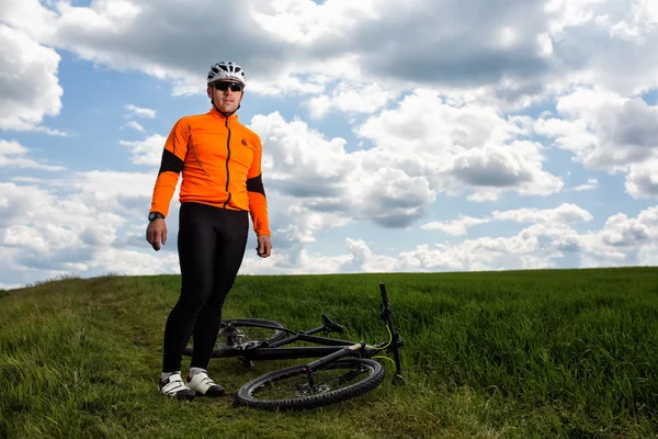 Young man cycling on a rural road through green meadow