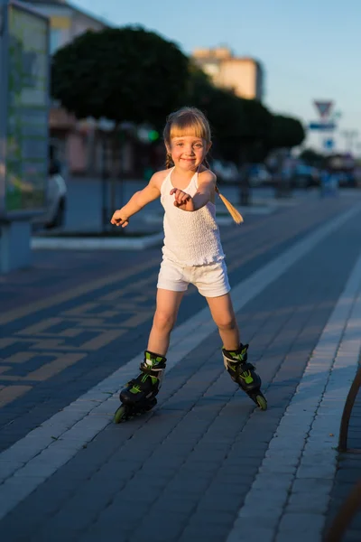 Little pretty girl on roller skates at a park