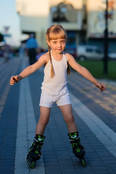 Little pretty girl on roller skates at a park