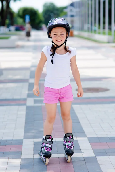 Little girl rides on roller skates at park