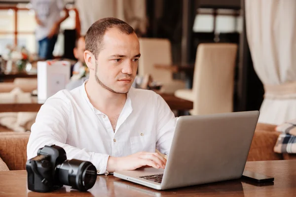 Photographer with the camera works on his laptop