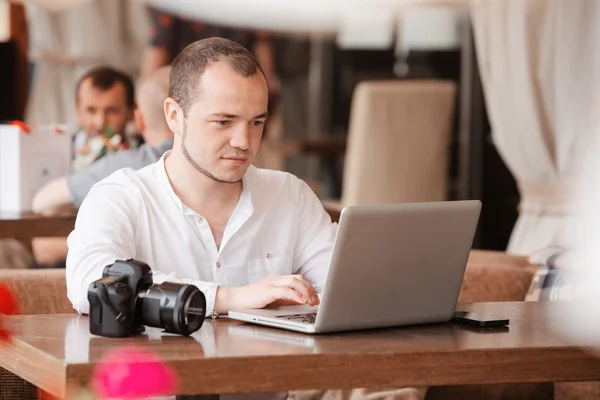 Photographer with the camera works on his laptop
