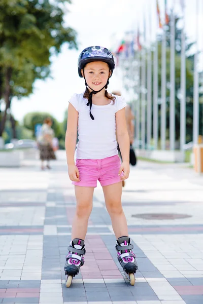 Little girl on roller skates in helmet at a park