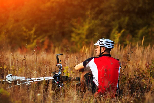 Cyclist with bike relax in the sunny autumn park