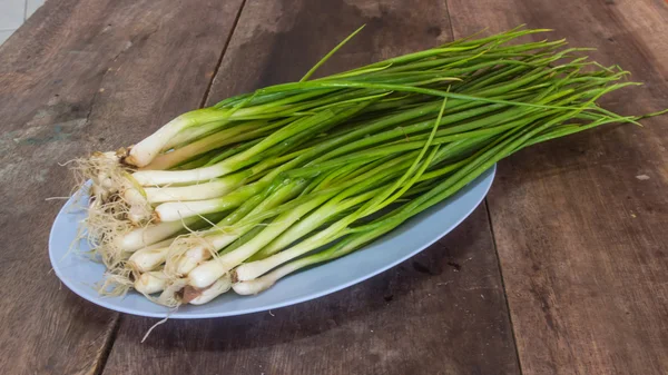 Beautiful spring onions on a plate on a wooden table.