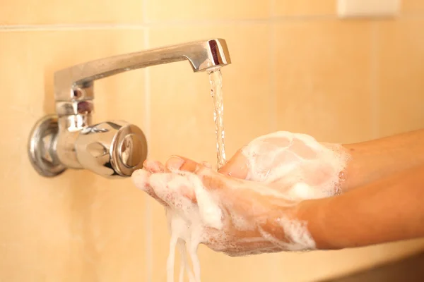 Human hands being washed under stream of pure tap water