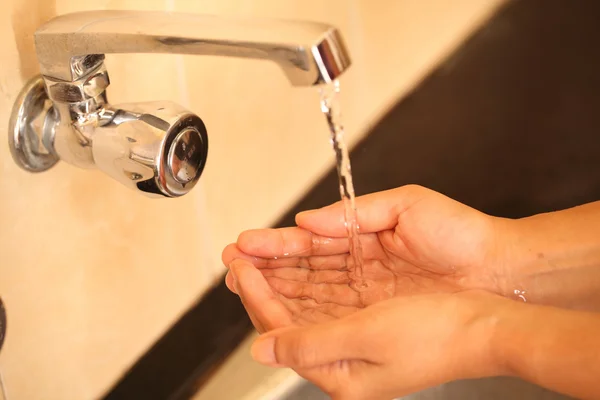 Human hands being washed under stream of pure tap water