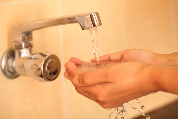 Human hands being washed under stream of pure tap water