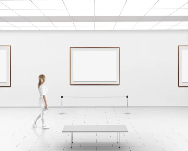 Woman walk in museum hall blank wall with frames