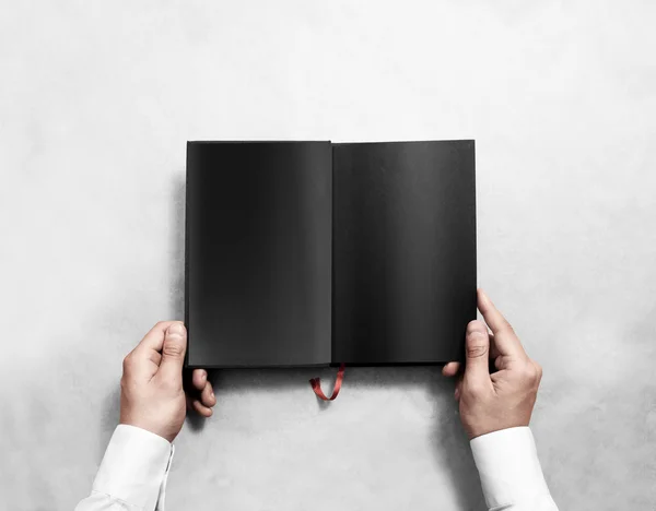 Hand holding blank opened book mock up with black pages.