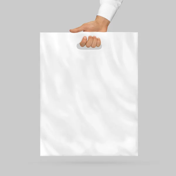 Blank plastic bag mock up holding in hand. Empty polyethylene package mockup hold in hands isolated on white. Consumer pack ready for logo design or identity presentation. Product food packet handle.